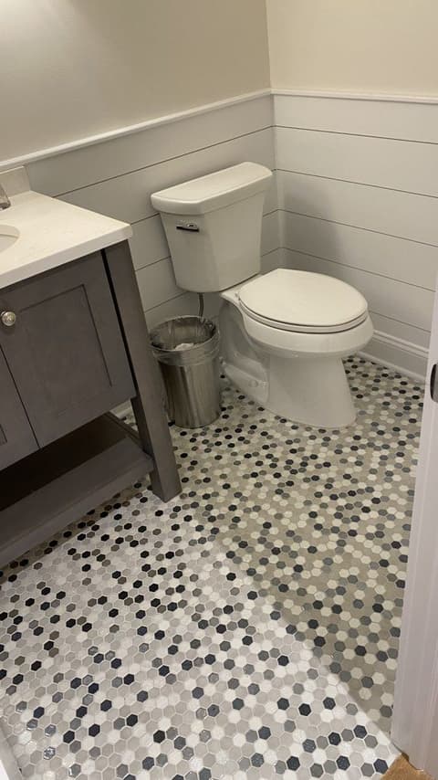 A guest bathroom in a Westfield, NJ new-construction home before renovation, with shiplap wainscot, a gray-stained vanity and a pebble mosaic floor