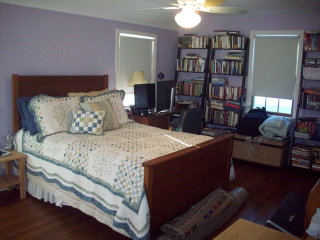 The primary bedroom of a Westfield, NJ home before renovation, with a wooden sleigh bed between crowded bookshelves