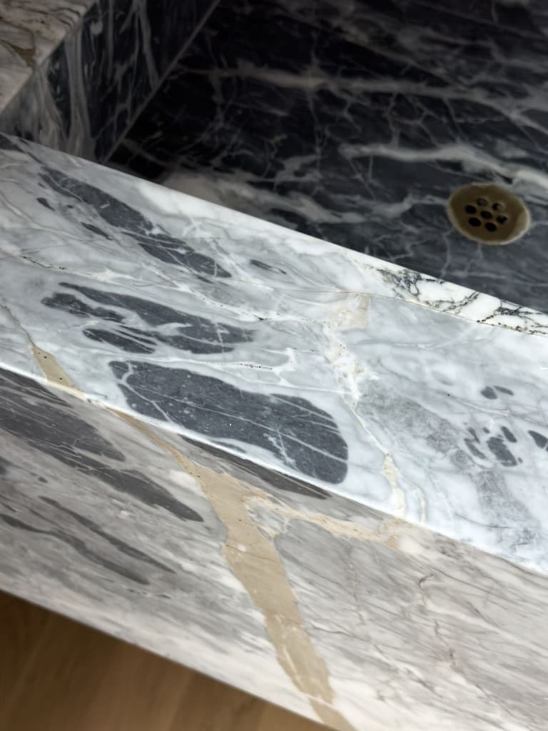 Mitered edge of a black and gold marble washstand in a Mendham, NJ renovation, with the veining carried across the corner