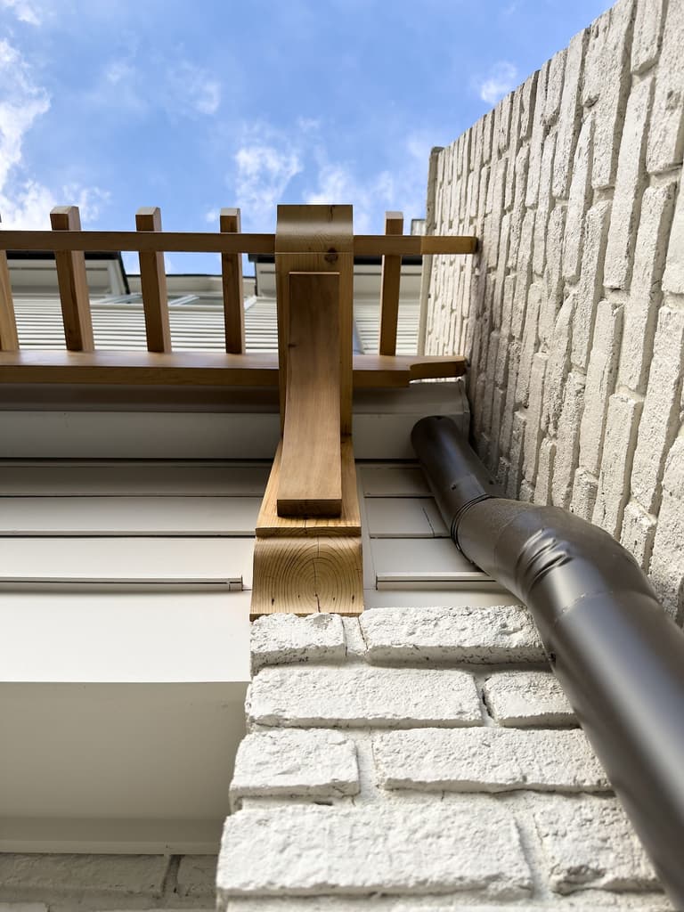 Cedar pergola bracket and lattice meeting painted brick above a doorway in a Mountainside, NJ exterior renovation by Michael Robert Construction