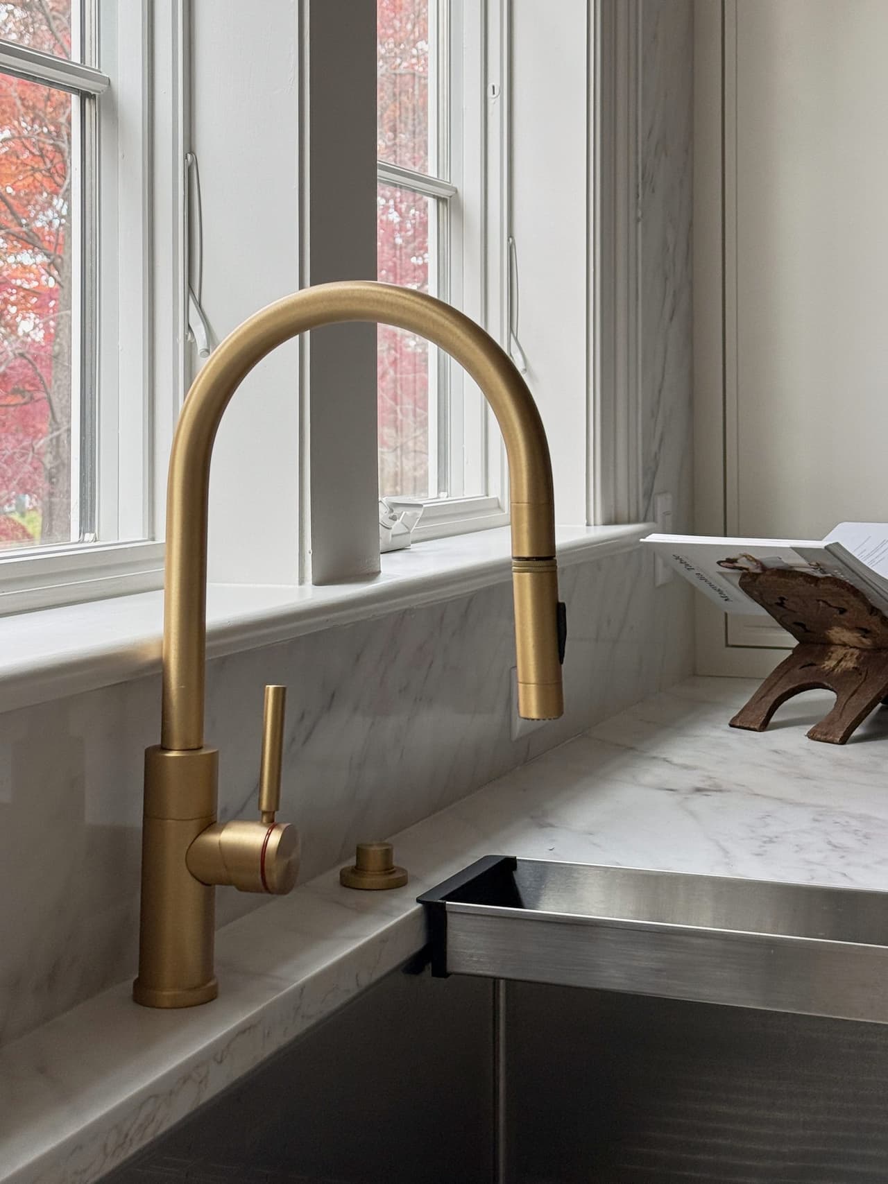 Brass pull-down faucet on marble above a stainless sink in a Summit, NJ kitchen by Michael Robert Construction