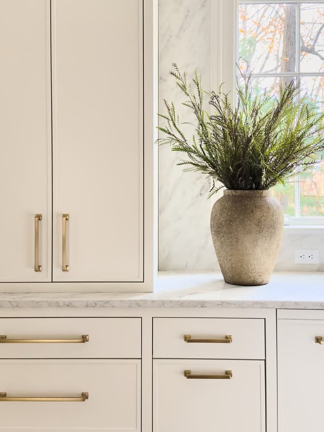 Cream kitchen cabinetry with long brass pulls beneath a marble counter in a luxury Summit, NJ home renovation by Michael Robert Construction
