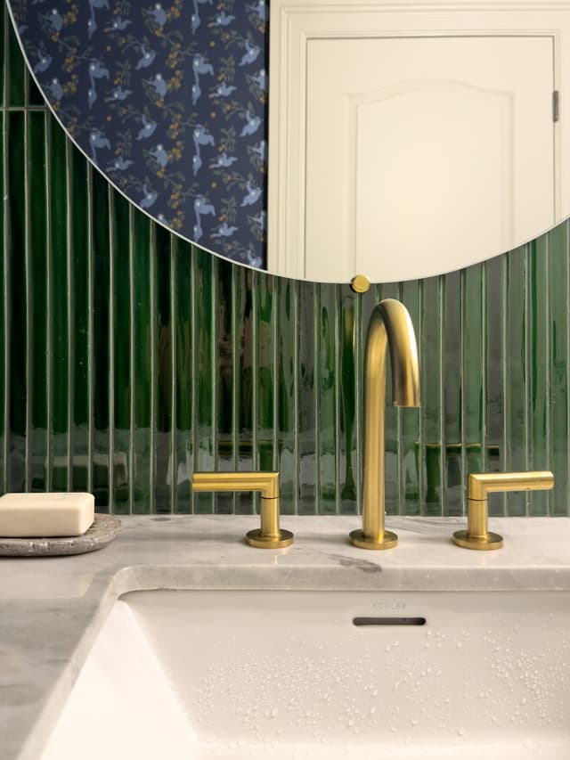 Brass widespread tap on a marble counter against emerald ribbed tile in a luxury Summit, NJ powder room renovation