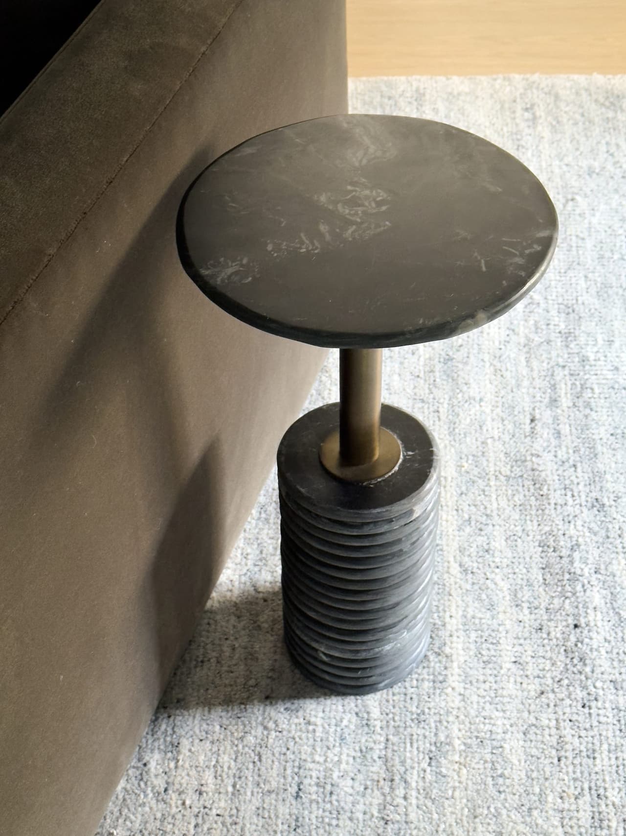 Ribbed stone side table on a brass stem beside a linen-skirted sofa in a Summit, NJ living room by Ellie Mroz Design