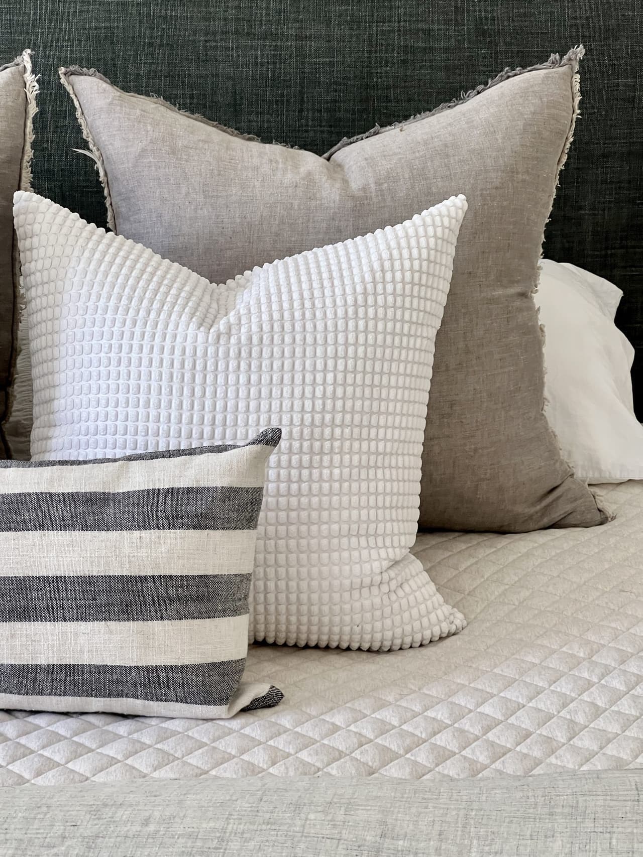 Linen, waffle-weave and striped pillows on a quilted coverlet in a Westfield, NJ bedroom by Ellie Mroz Design