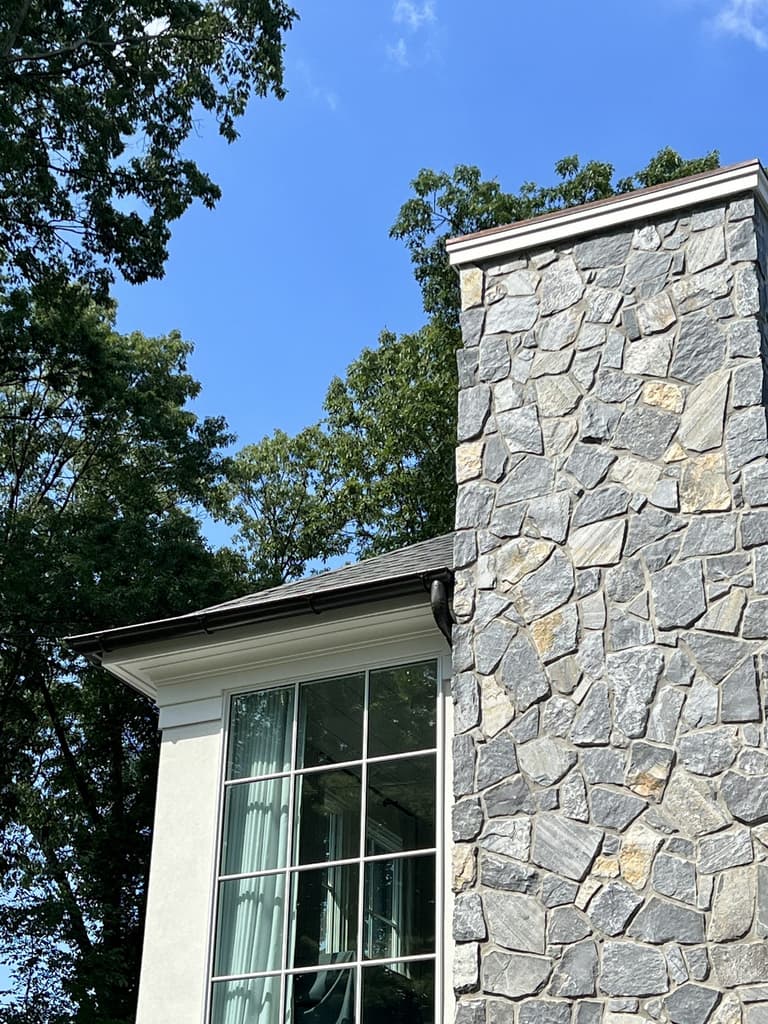 Stone chimney meeting clapboard siding and the roof edge at a Westfield, NJ renovation and addition by Michael Robert Construction