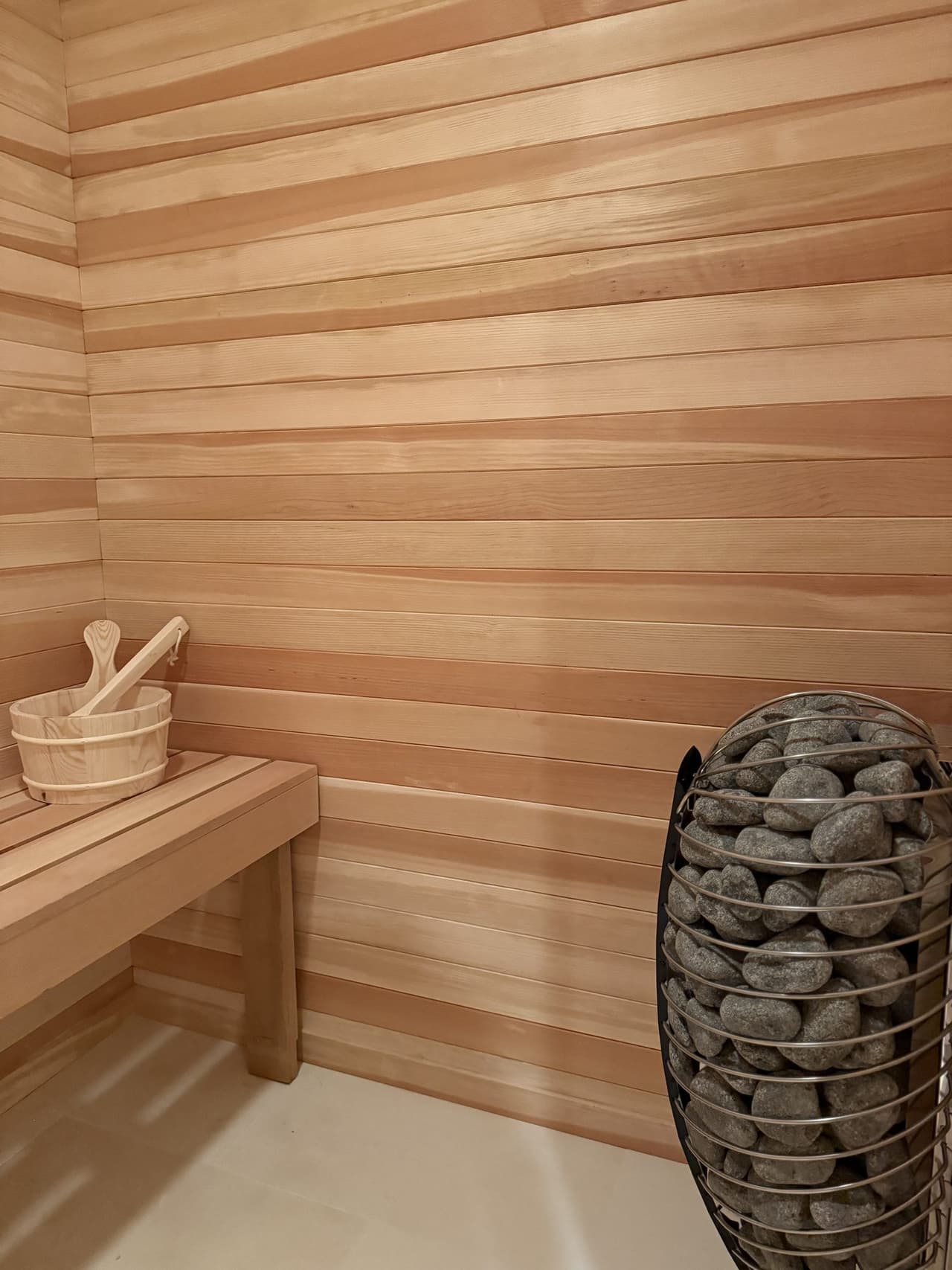 Cedar sauna interior with a bench and stone-filled heater in a Short Hills, NJ home by Michael Robert Construction