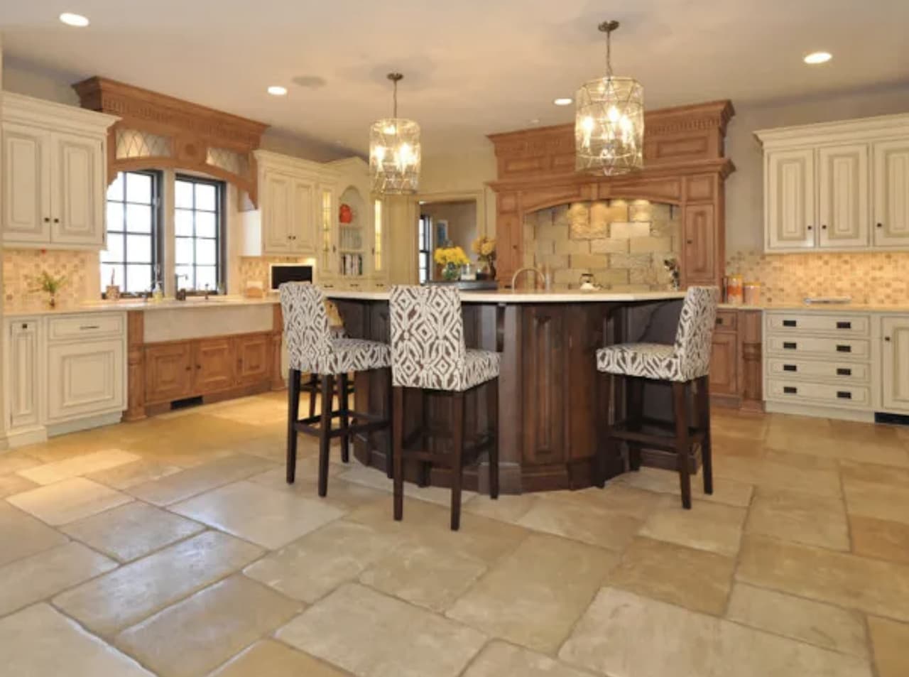 The kitchen of a luxury Summit, NJ home before renovation, with raised-panel oak and cream cabinetry, a tiled backsplash and a travertine floor