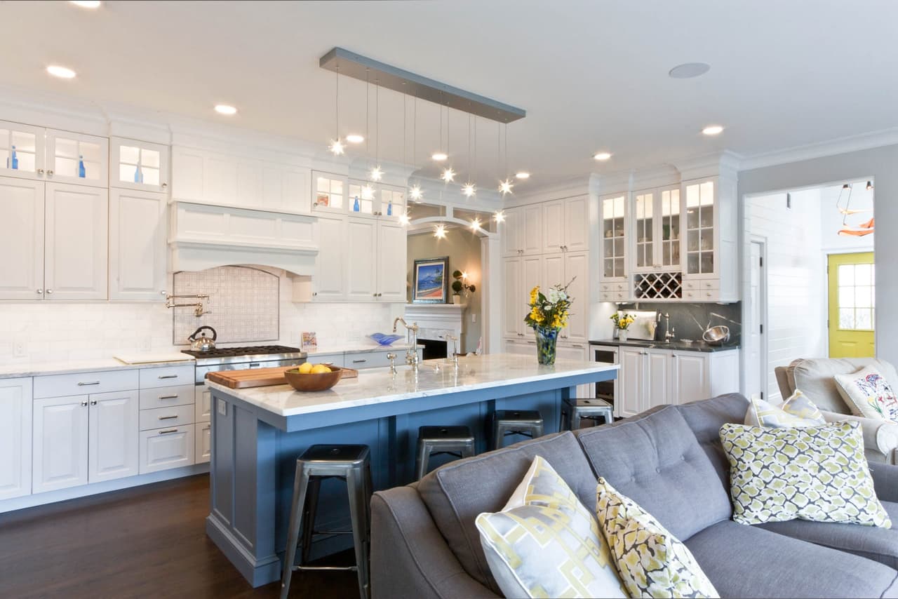 Kitchen and family room with a gray island, counter stools and a sectional sofa with patterned pillows