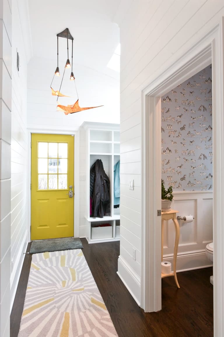 Mudroom hall with a yellow back door, shiplap, coat hooks and a powder room off to one side