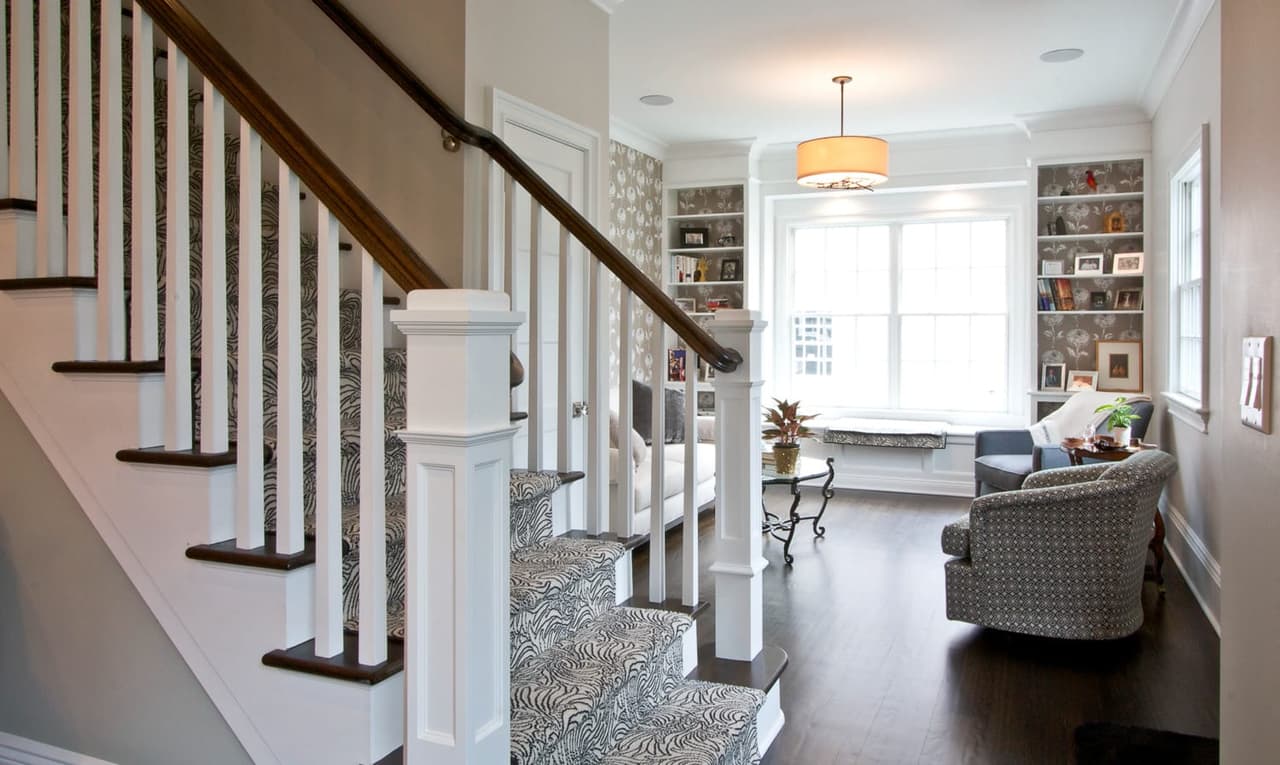 Stair with a dark handrail and white balusters, looking through to a built-in window seat