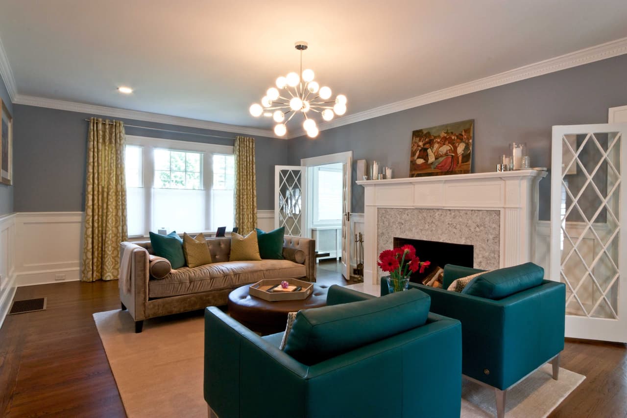 Living room with a tiled fireplace, leaded-glass built-ins, teal armchairs and a coffered ceiling
