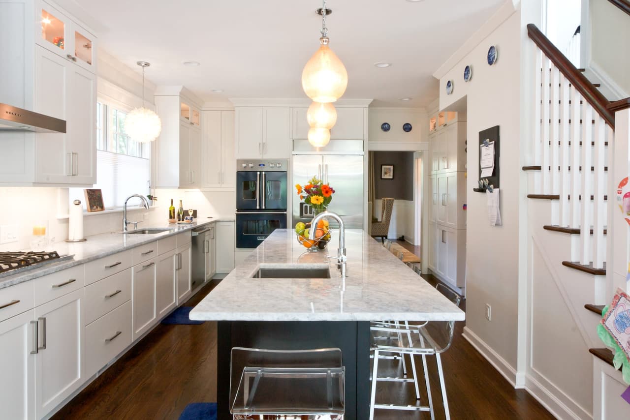 Kitchen with white perimeter cabinetry, a dark marble-topped island and acrylic counter stools