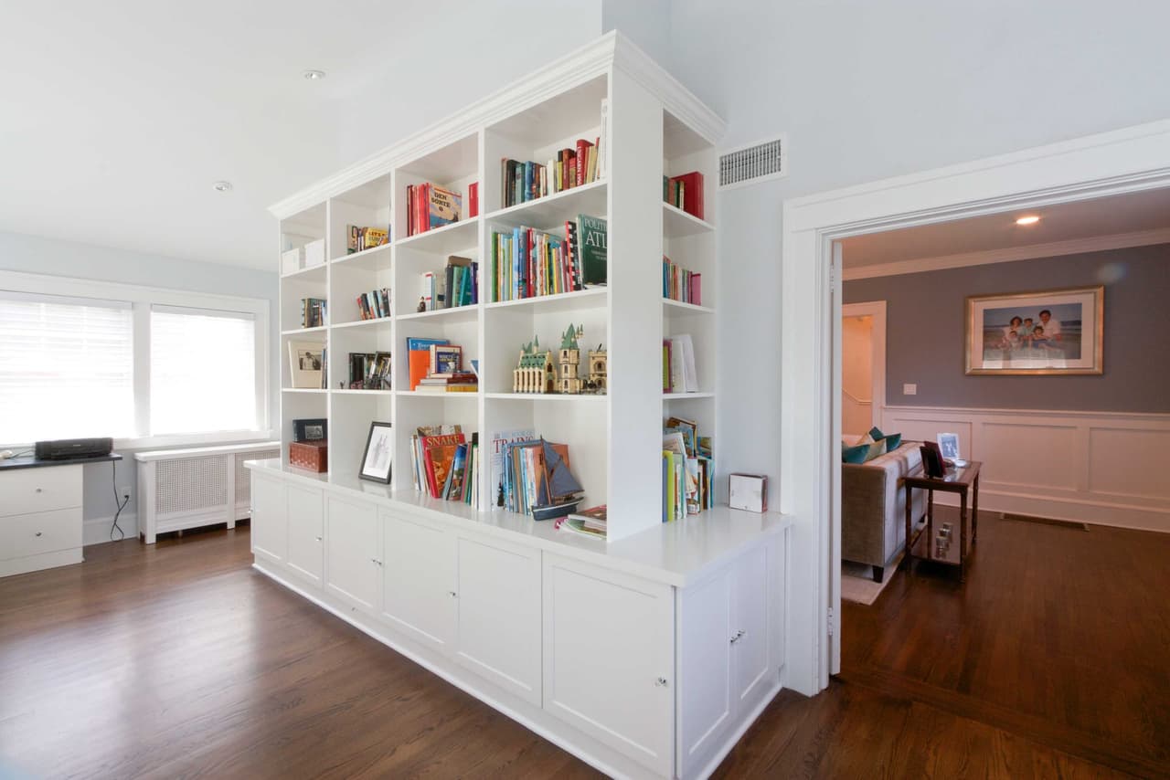 Built-in bookcase wall with cabinet storage below, framing an opening into the next room