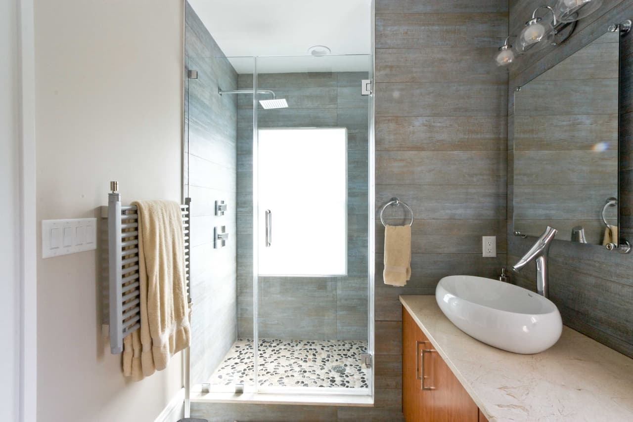 Bathroom with a glass shower, gray plank-look tile, a pebble shower floor and a vessel sink