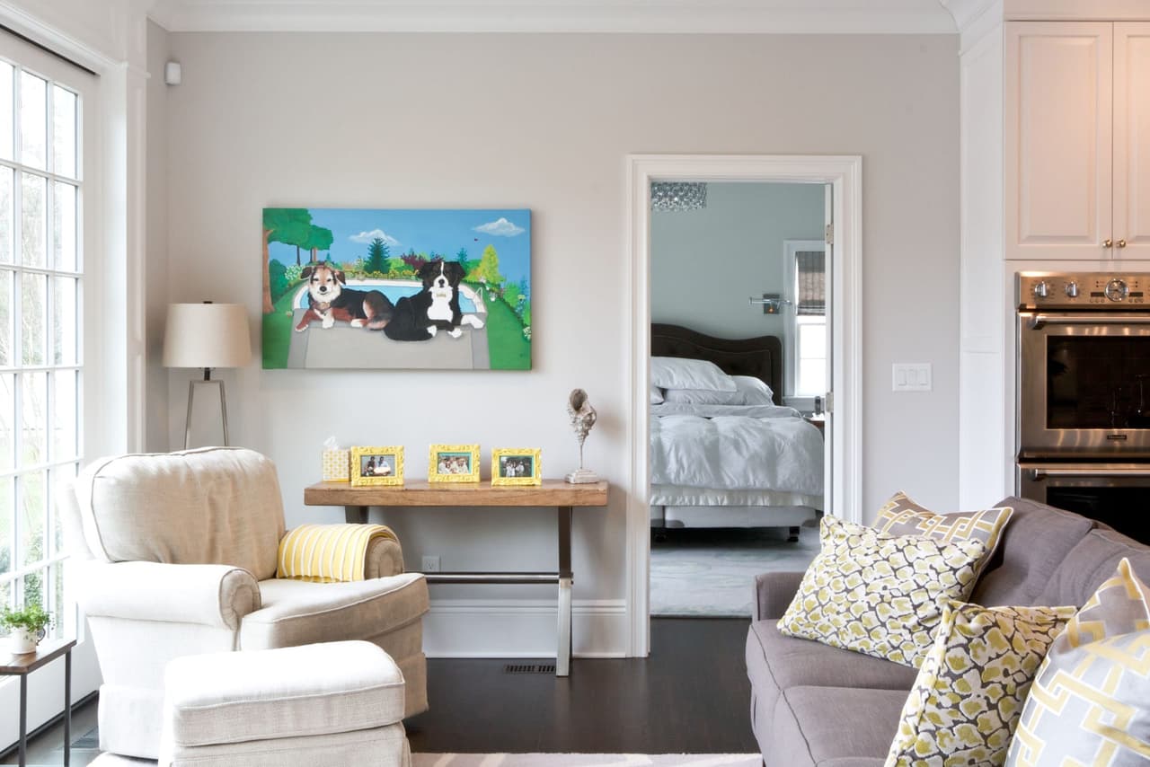 Family room with a slipcovered armchair, a wood counter behind the sofa and a view through to the bedroom