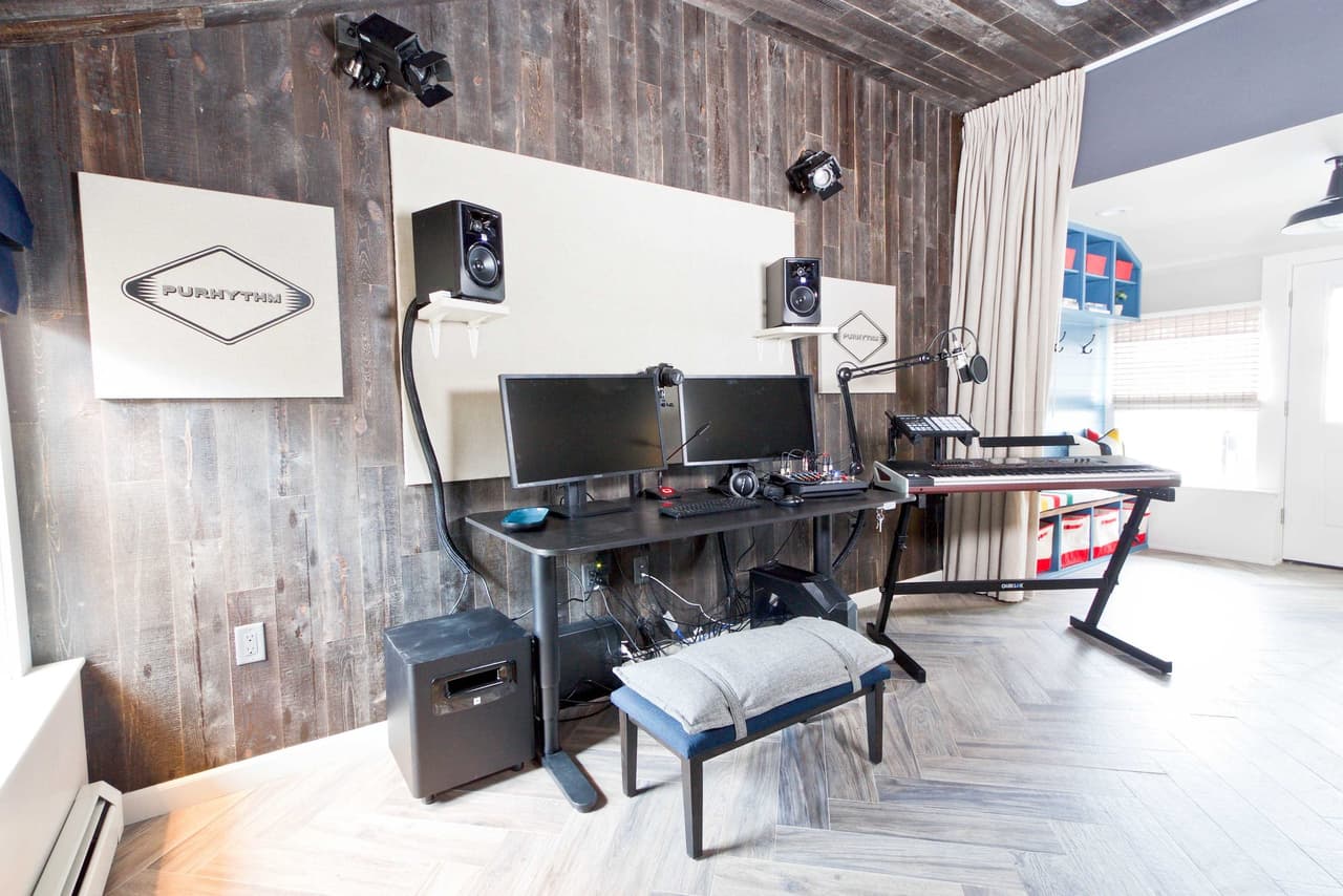 Lower-level office with a reclaimed plank accent wall, two desks, monitors and wall-mounted speakers