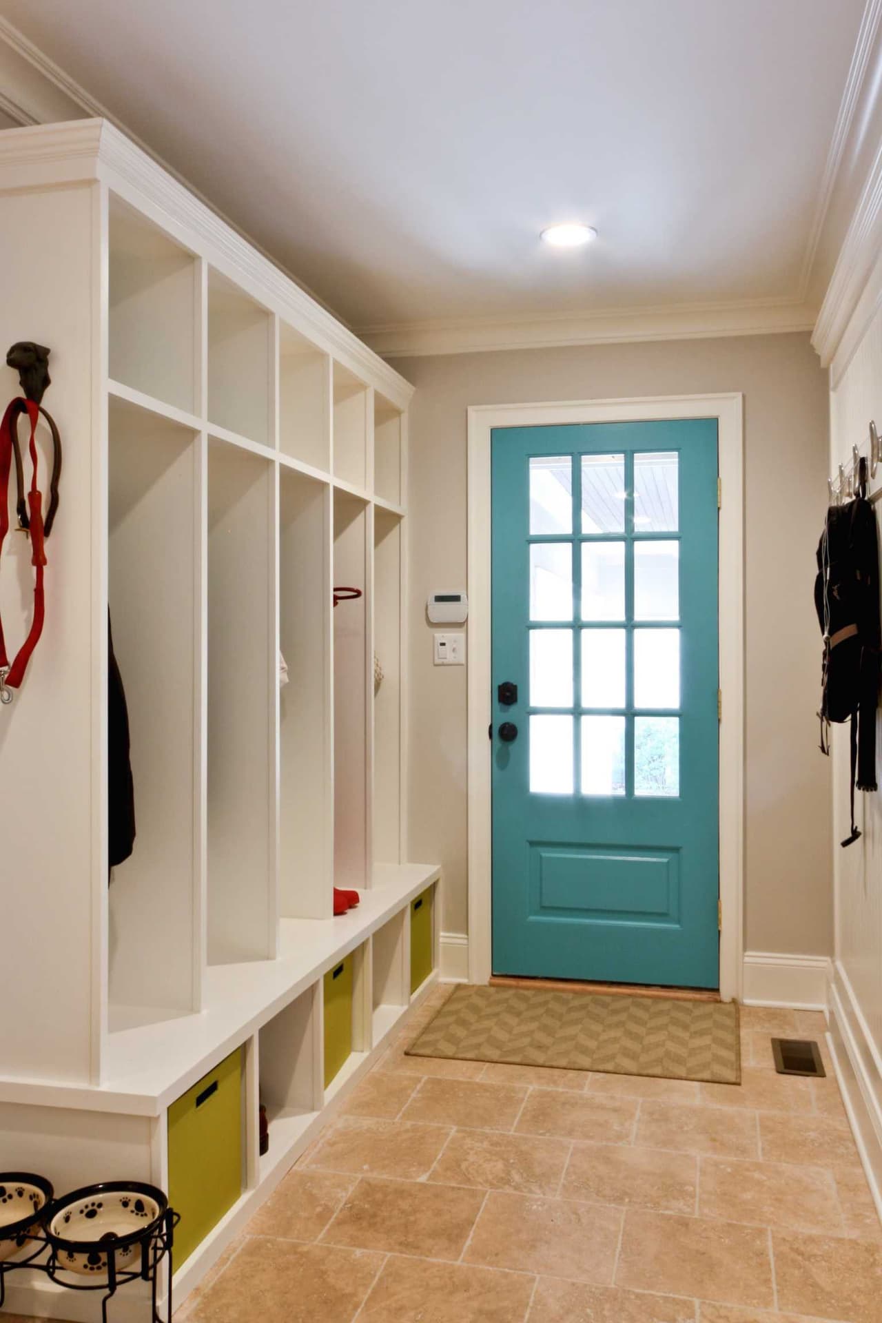 Mudroom of a Westfield, NJ coastal colonial renovation, with white open lockers, cubbies above and a turquoise glazed back door onto the terracotta tile floor