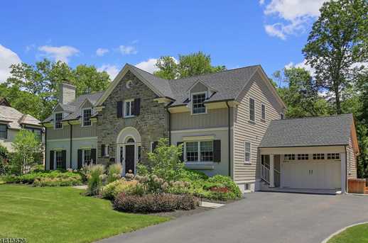 Front of a fieldstone and shingle Westfield, NJ home after renovation and addition, with a pedimented entry, bay windows and an attached garage