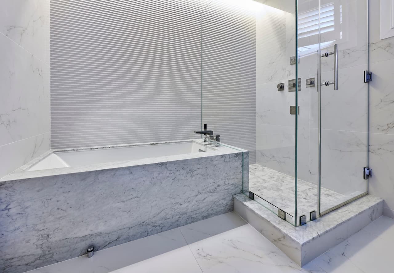 Marble-clad tub deck beside a glass shower in a Westfield, NJ primary suite, with a fluted tile panel behind the tub