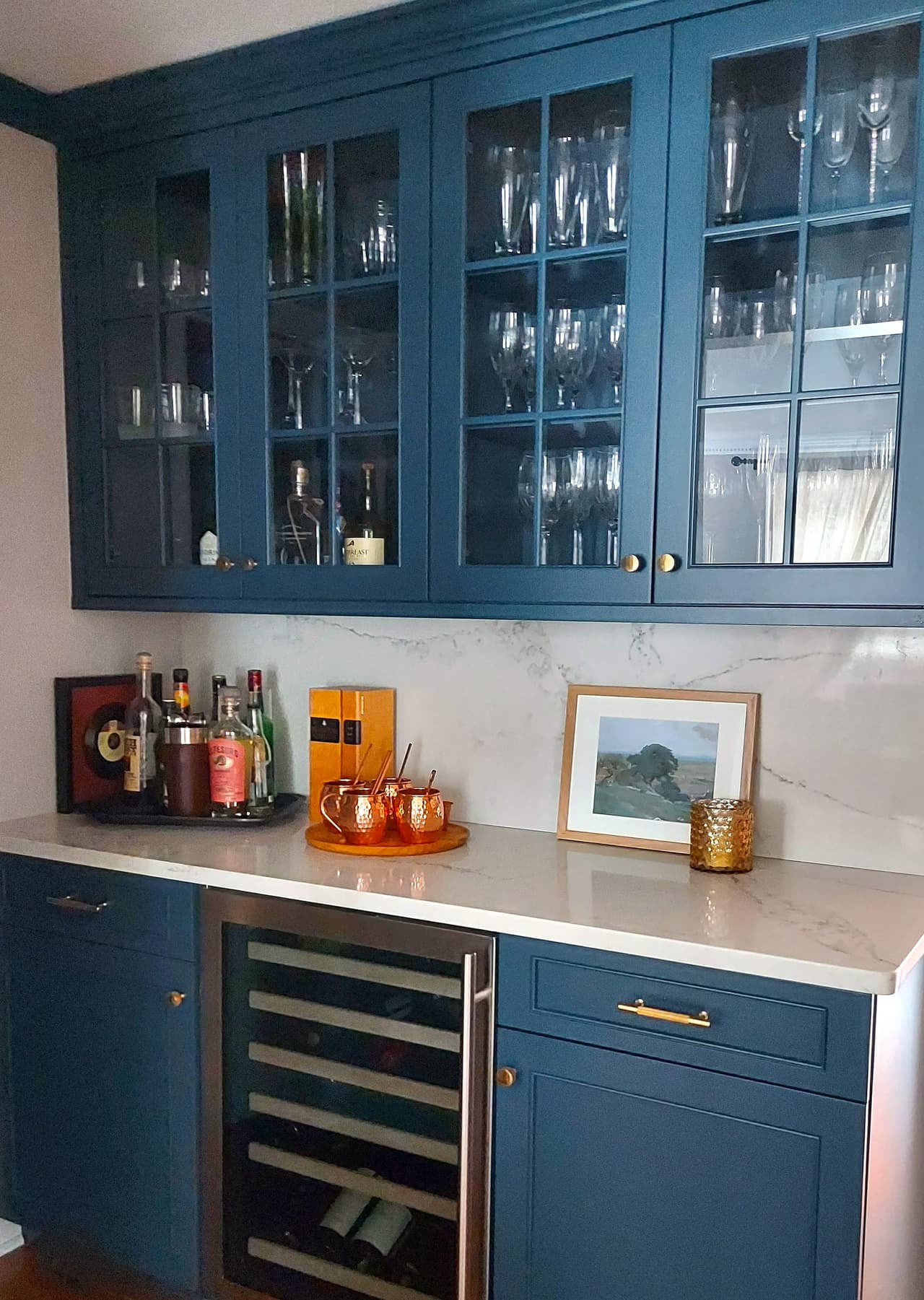 Butler's pantry with navy base cabinets, glass-front uppers, a marble counter and an undercounter wine refrigerator