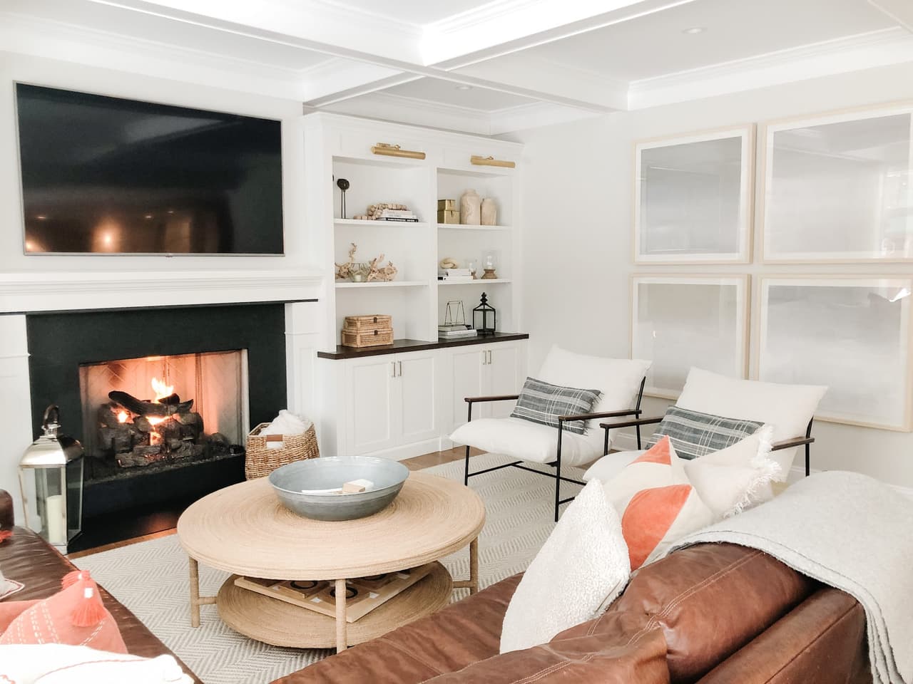 Family room with a brick-lined fireplace, white built-in shelving and a round travertine coffee table