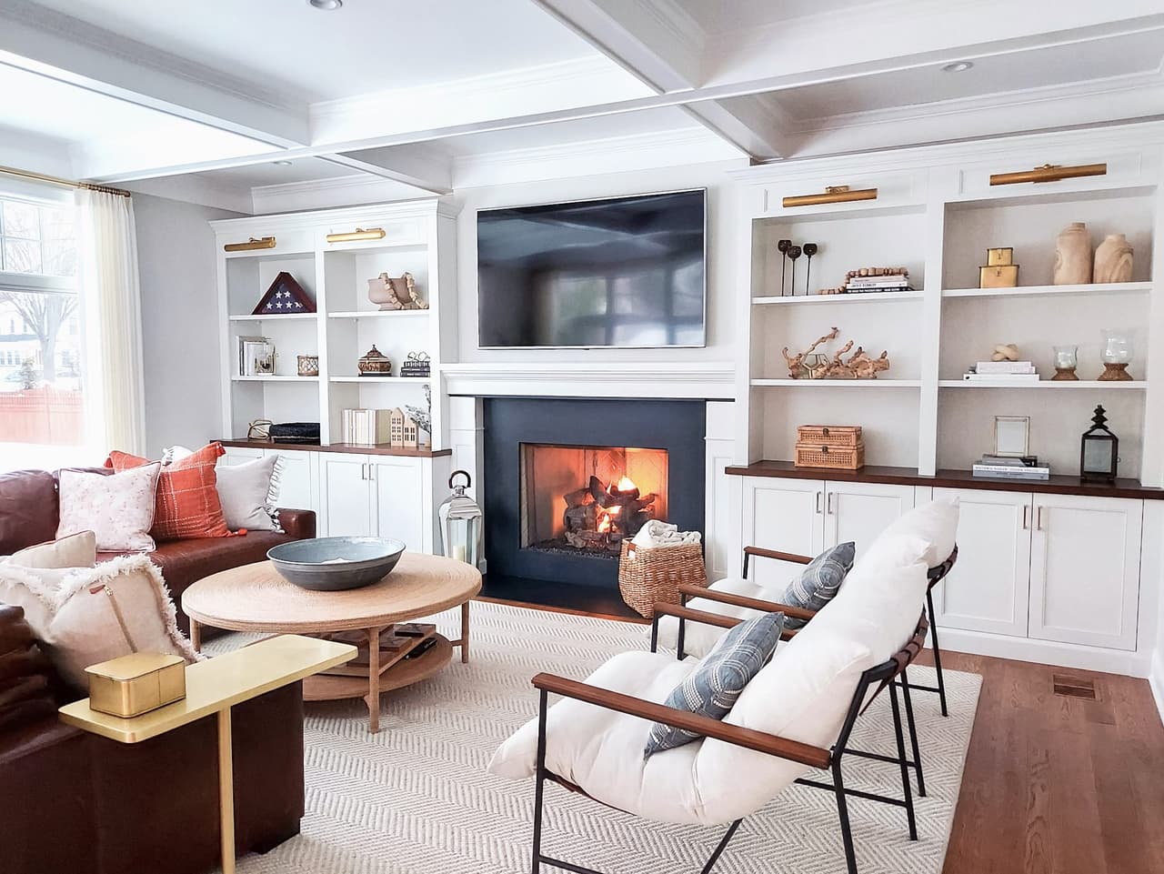Fireplace end of a Westfield, NJ family room, with white built-in shelving either side of the chimney breast and two spindle chairs facing the sofa