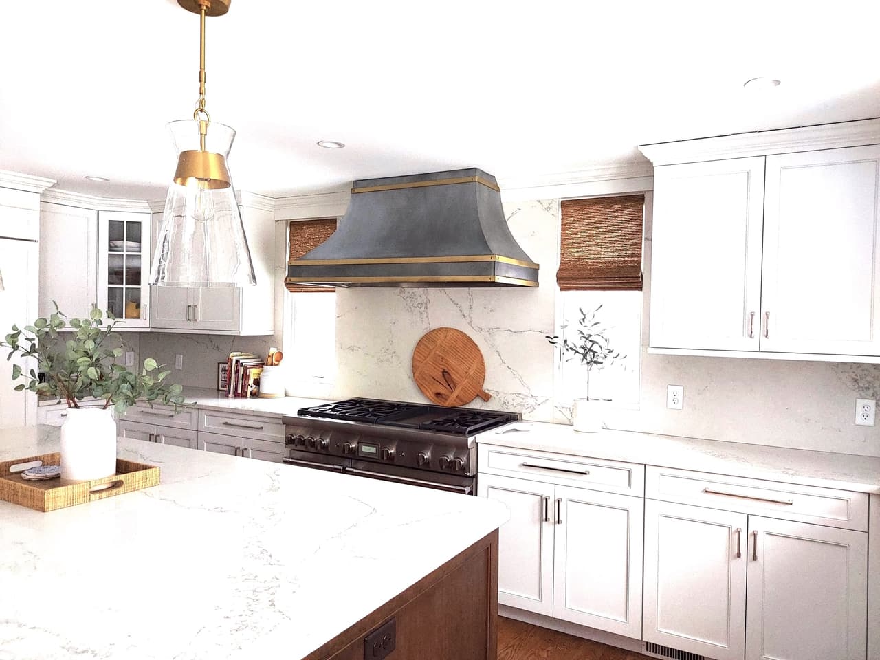 Range wall with a zinc-and-brass hood, a professional range and marble counters, with woven shades at the window