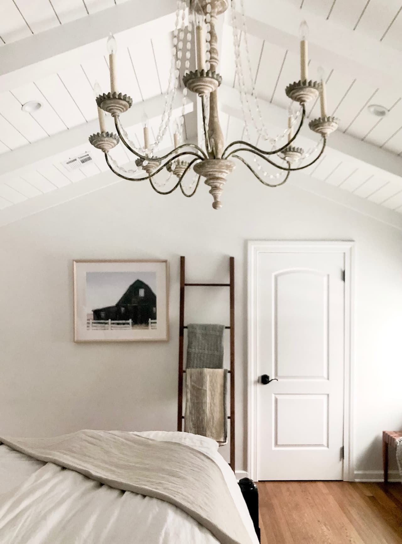Primary bedroom with a planked vaulted ceiling, an antique brass chandelier and a ladder blanket rail
