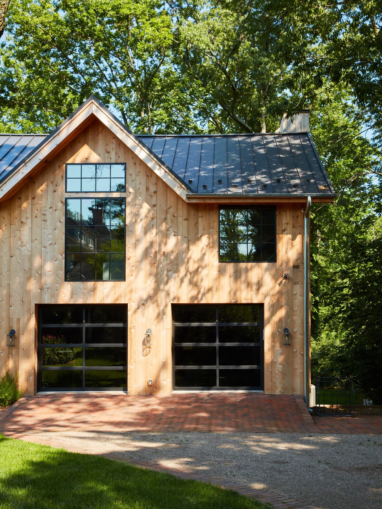 Cedar-clad barn with a standing-seam roof, black-framed glazed carriage doors and a brick apron in Westfield, NJ