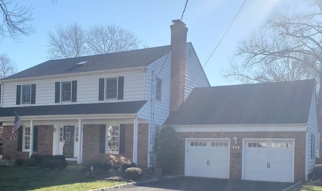 The front and garage wing of a Westfield, NJ colonial before its exterior renovation, with a flat porch roof over the entry and no stone to the first storey