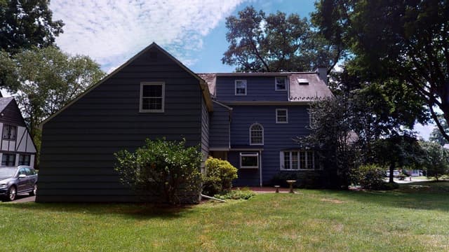 The Westfield, NJ house before its exterior renovation, dark-stained siding under a steep gable with the garage wing to the left