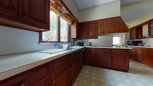 The kitchen of a Westfield, NJ home before renovation and addition, with cherry cabinetry, a soffit over the wall units and a vinyl floor
