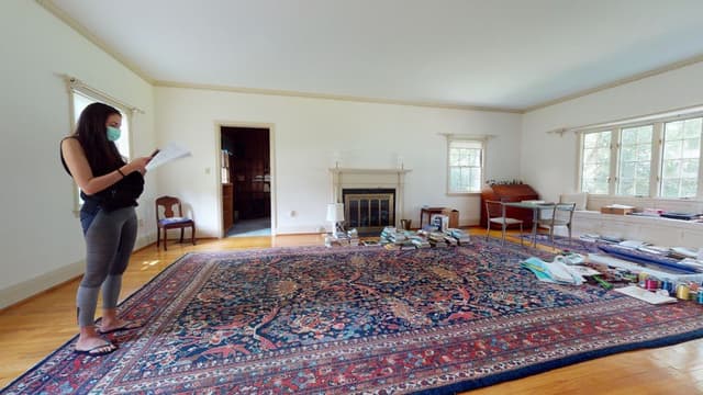 The living room of a Westfield, NJ home before renovation and addition, with a white mantel, pale walls and a Persian rug over the boards