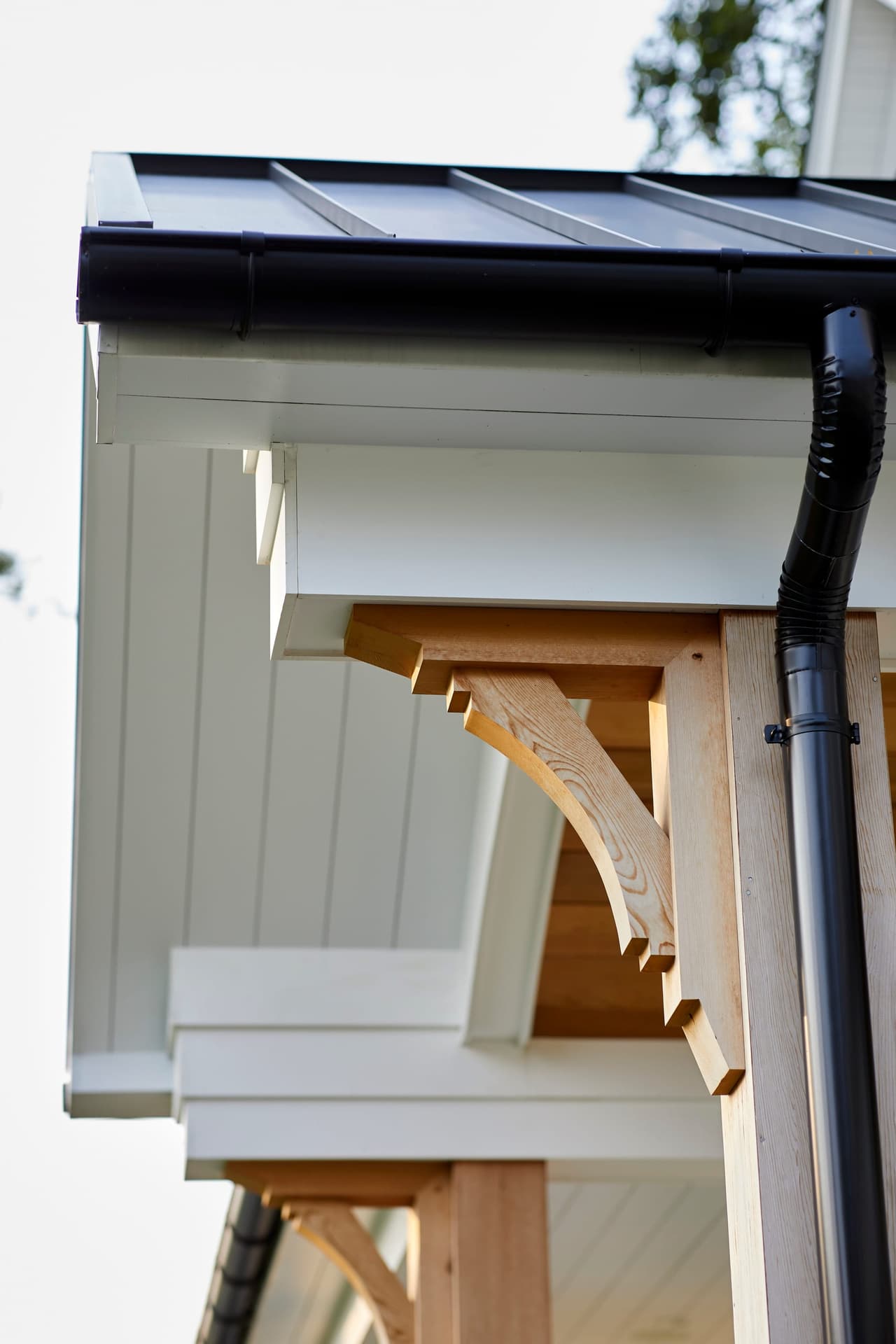 Detail of a bracketed eave and standing-seam porch roof against board-and-batten siding in Westfield, NJ