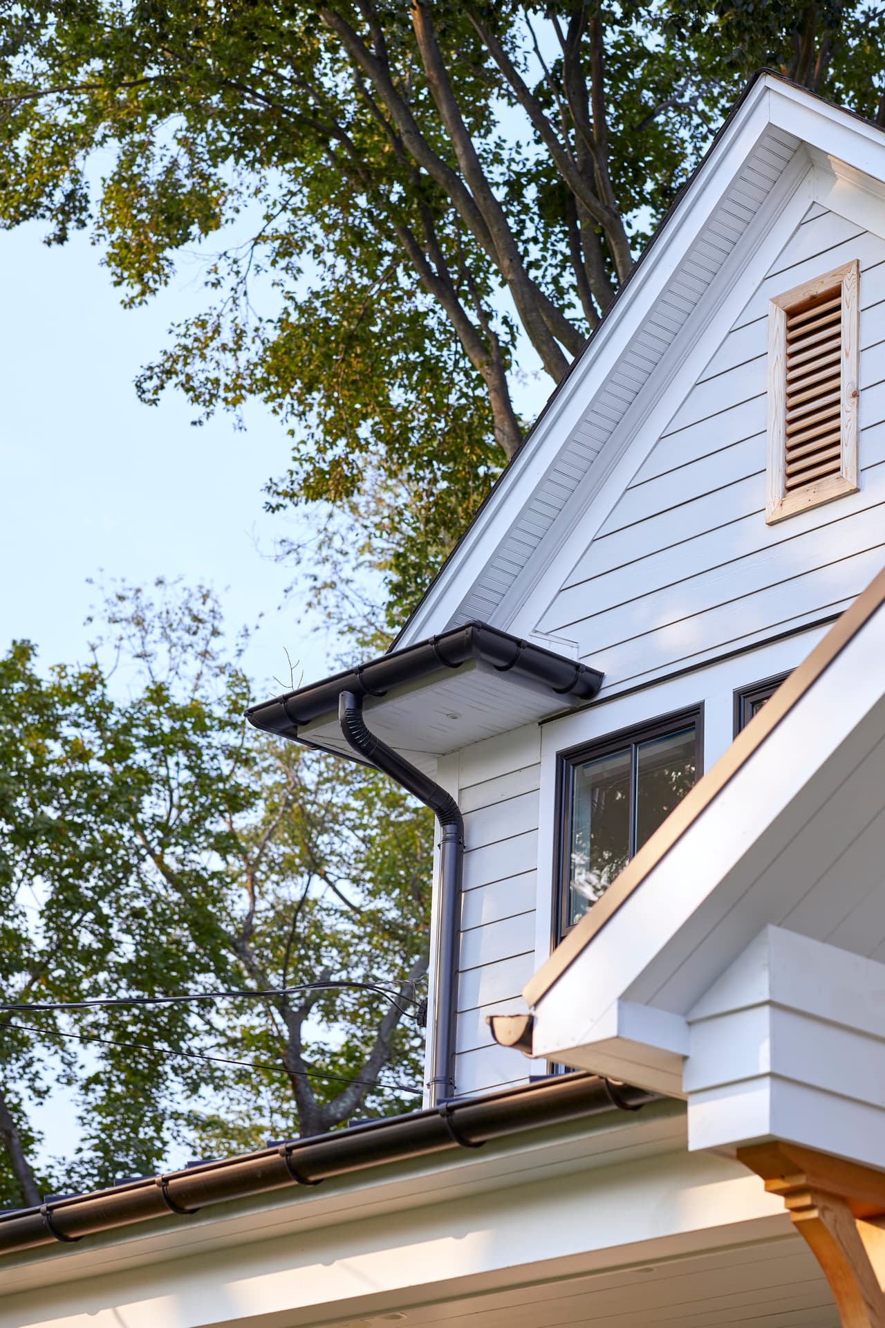 Cedar louvered gable vent and eave detail on a white board-and-batten elevation in Westfield, NJ