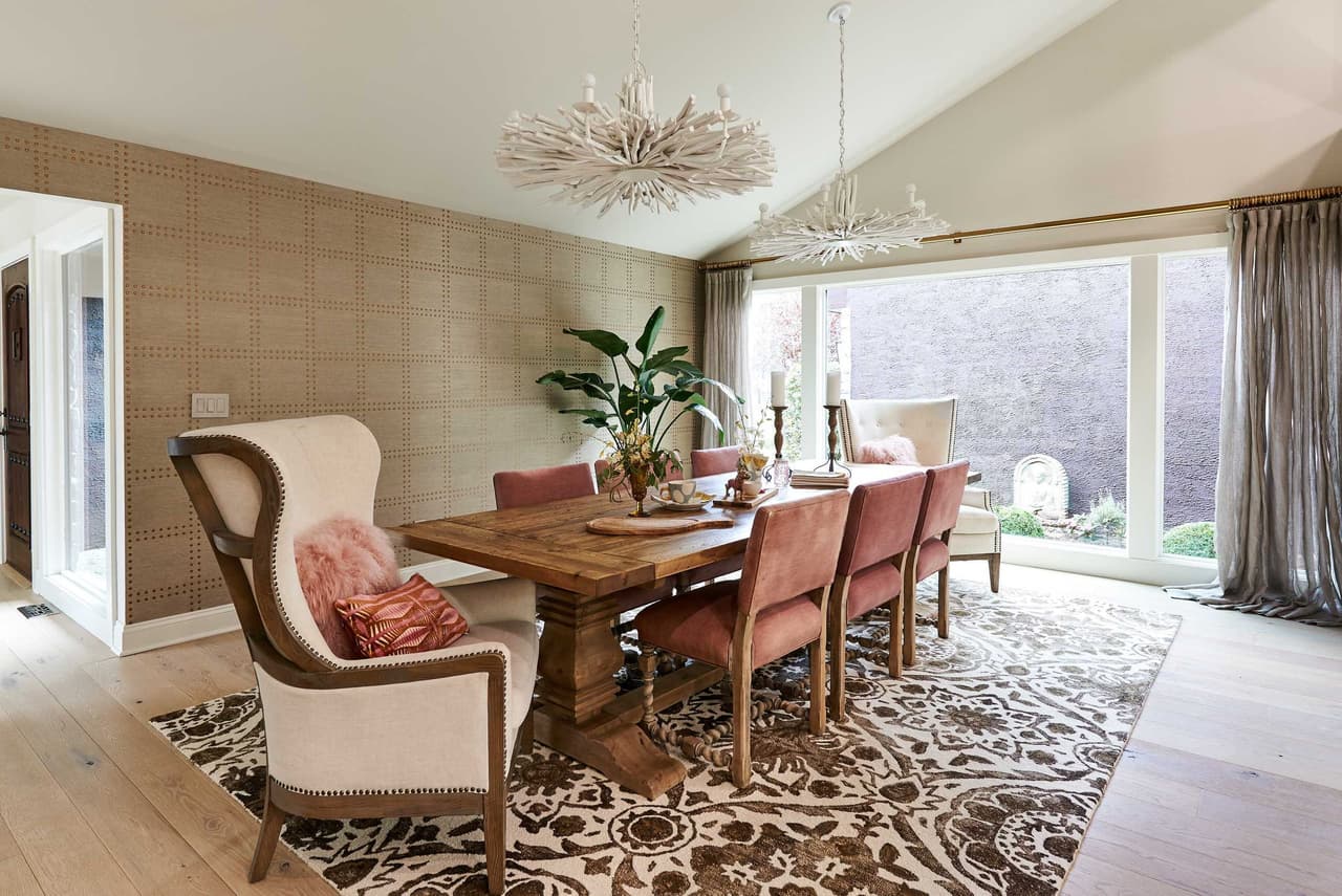 Dining room with a trestle table, a starburst pendant, grasscloth walls and a patterned rug