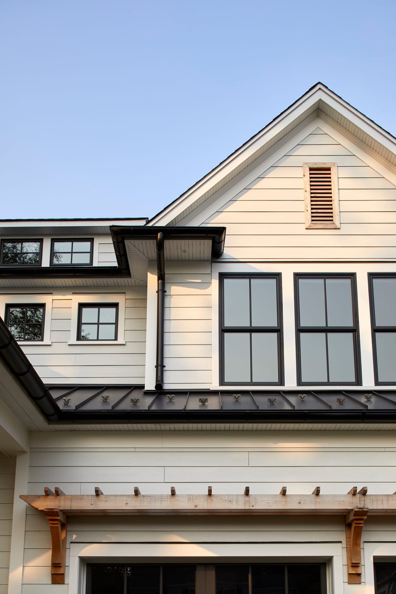 Gable end of a Westfield, NJ new-construction home, with bracketed eaves, a louvered attic vent and black-framed windows under a deep overhang