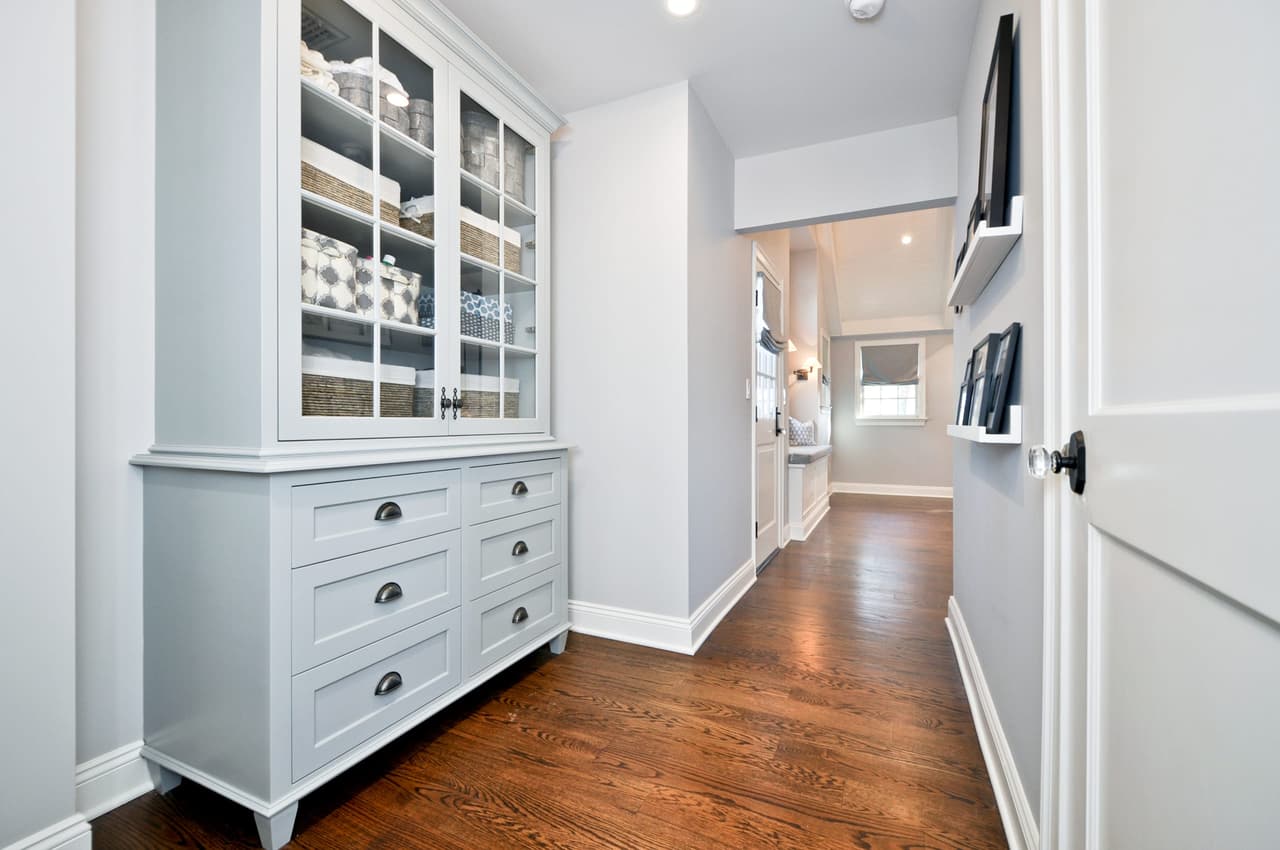 Linen hall with a built-in dresser below glass-front cabinets, lit from the window at the end