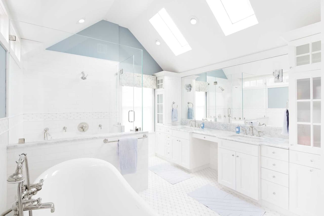 Primary bathroom under a vaulted ceiling with skylights, a freestanding tub and a double vanity