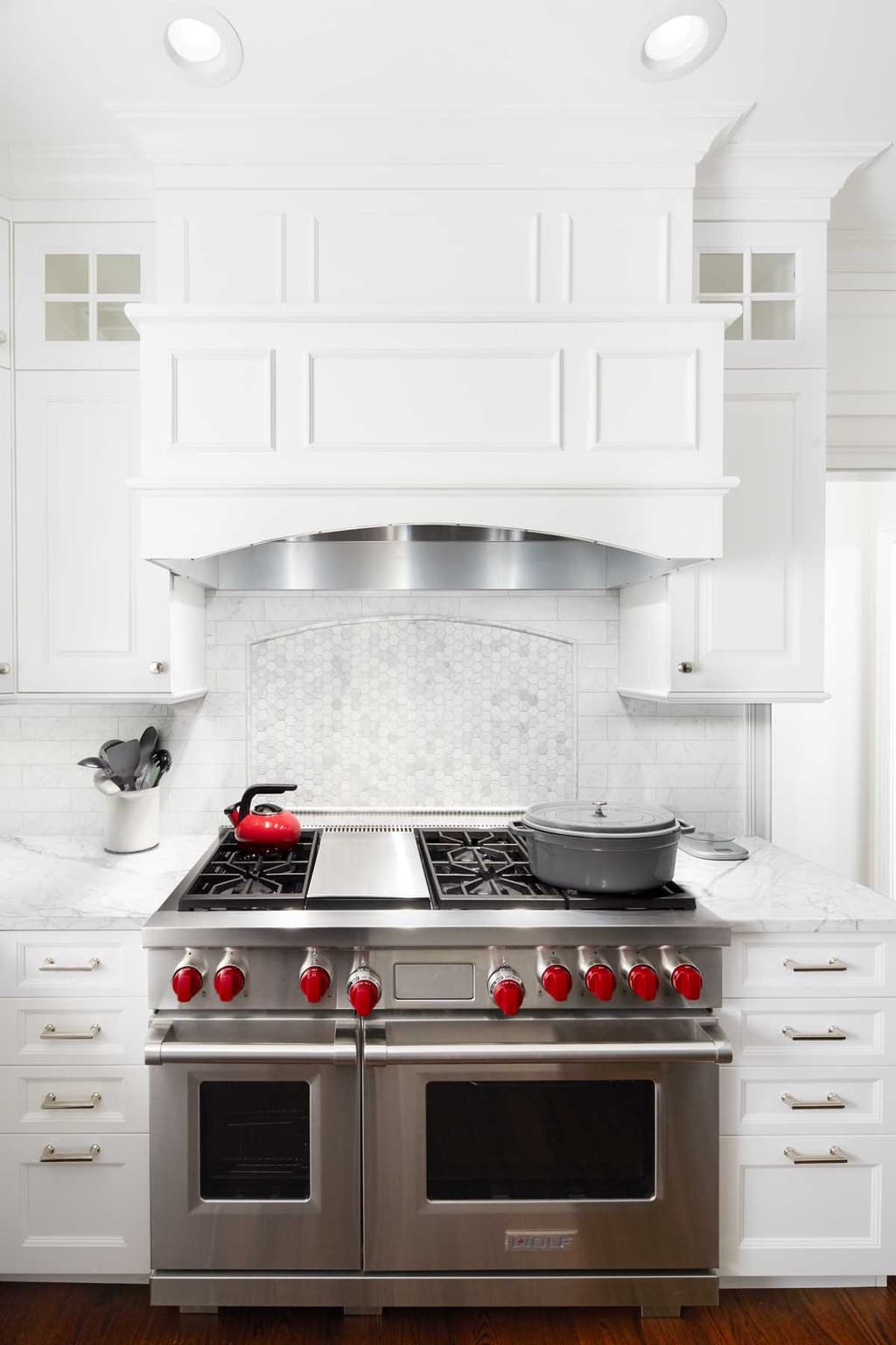 Range wall of a Westfield, NJ kitchen renovation, with a double range under a paneled hood between two mullioned cabinets