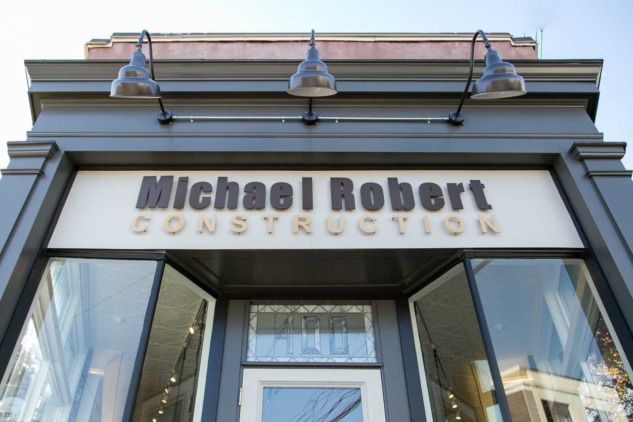 The Michael Robert Construction storefront sign and entry under gooseneck lights in Westfield, NJ
