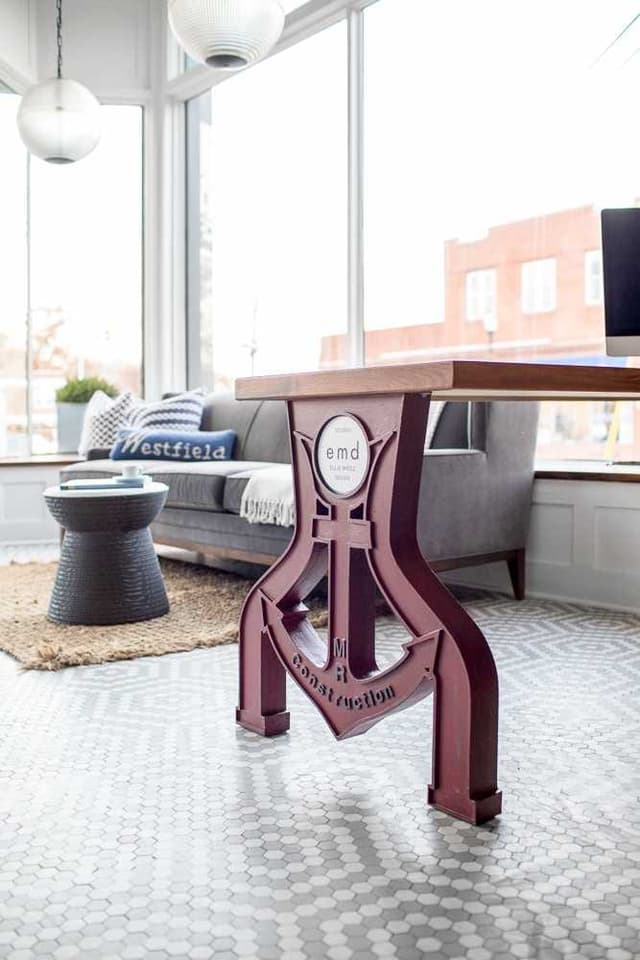 Meeting table on a cast-iron base in front of the studio's street-facing windows, on a patterned rug