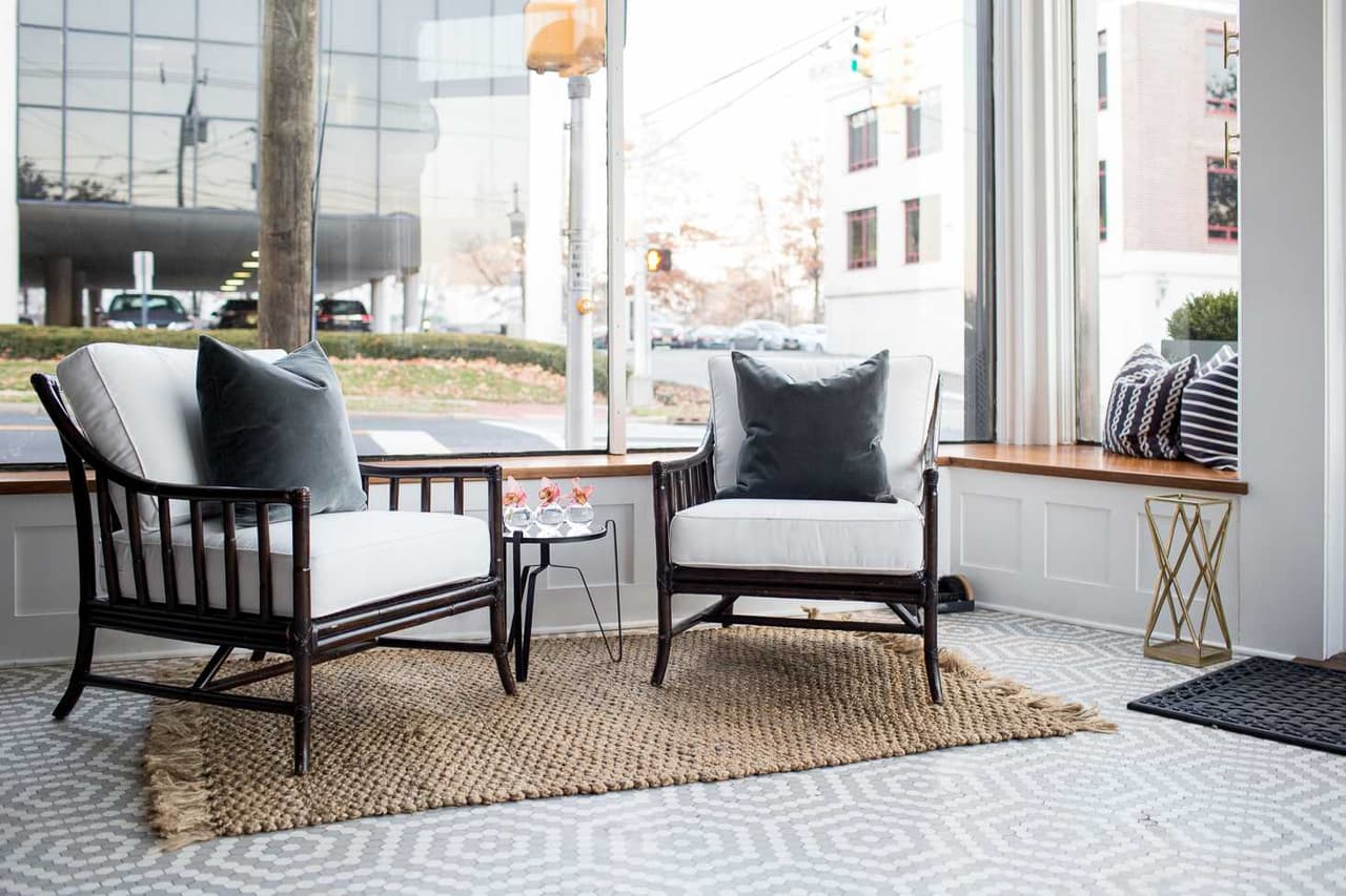 Seating area in the studio window with two black spindle chairs on a jute rug, looking onto the street