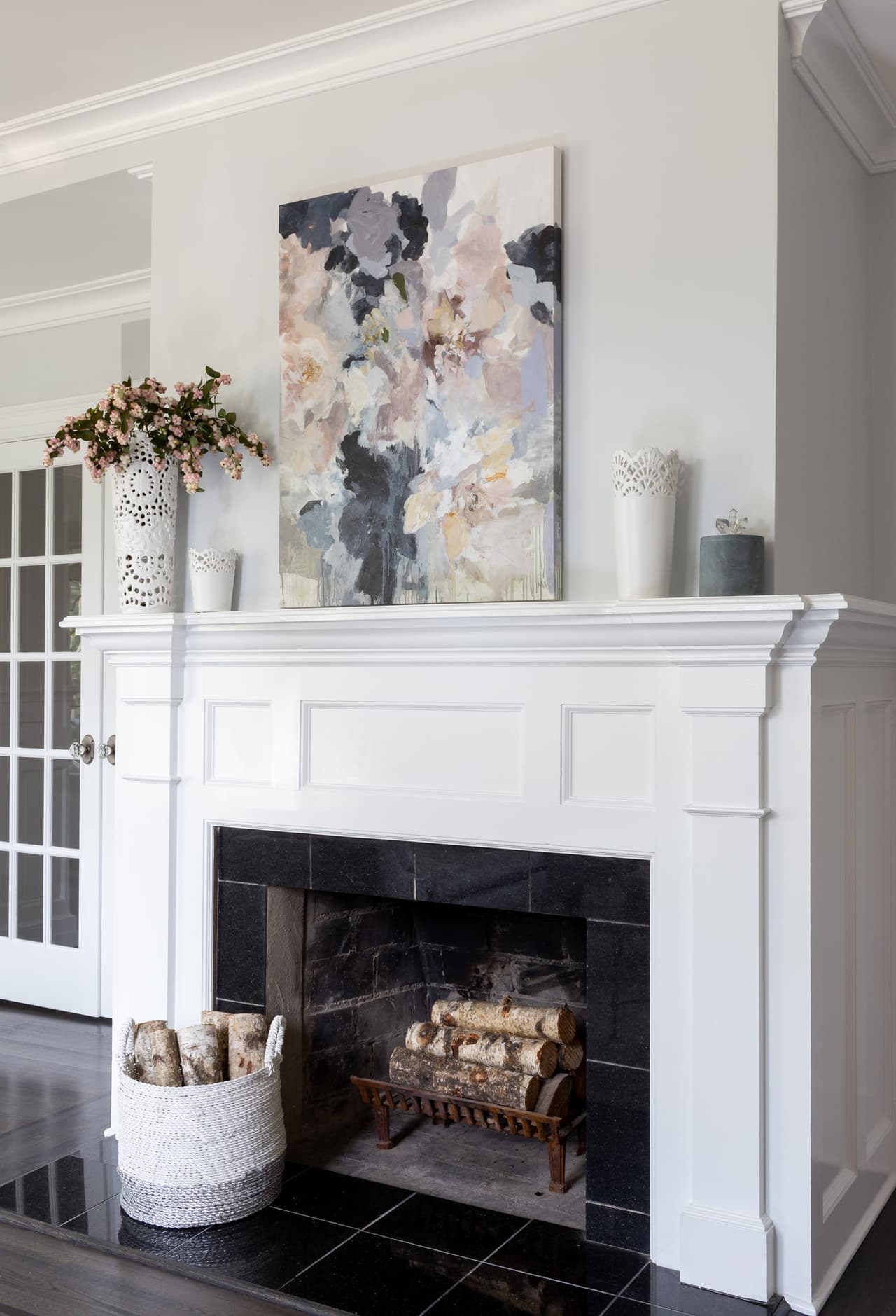 Fireplace with a white paneled overmantel, a dark tiled surround and a glass-front built-in cabinet beside it