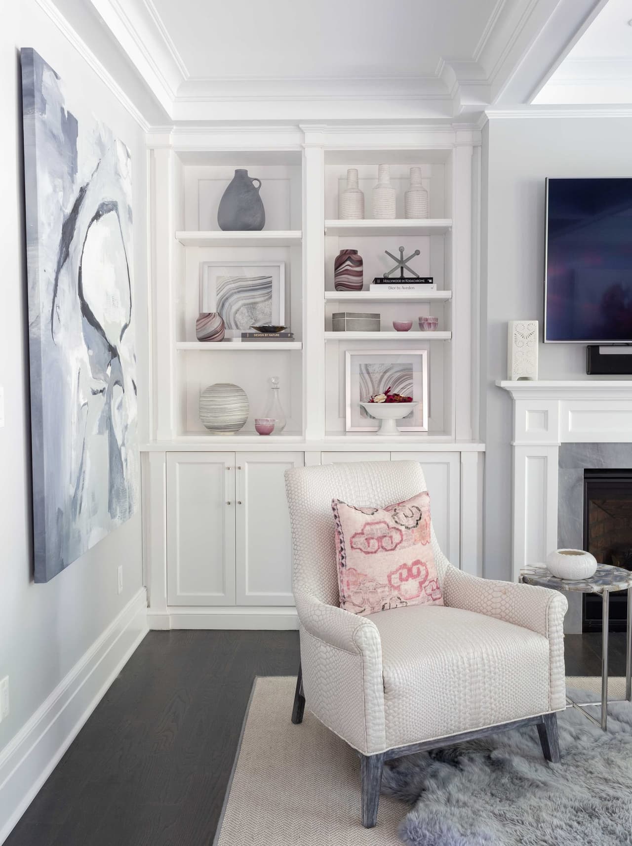 Sitting area with white built-in shelving and cabinetry flanking the fireplace, with a television set above the mantel