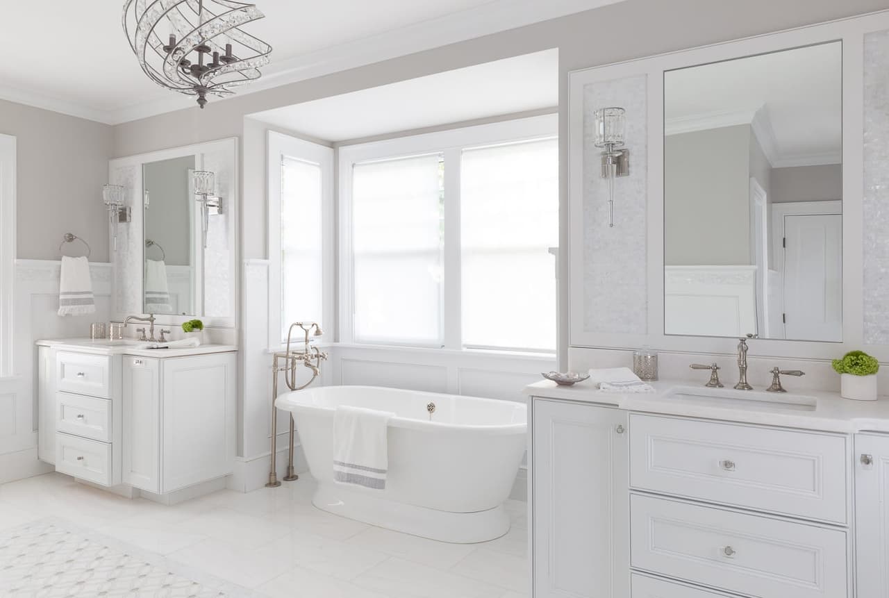 Primary bathroom with a freestanding tub set between two vanities, framed mirrors and patterned floor tile