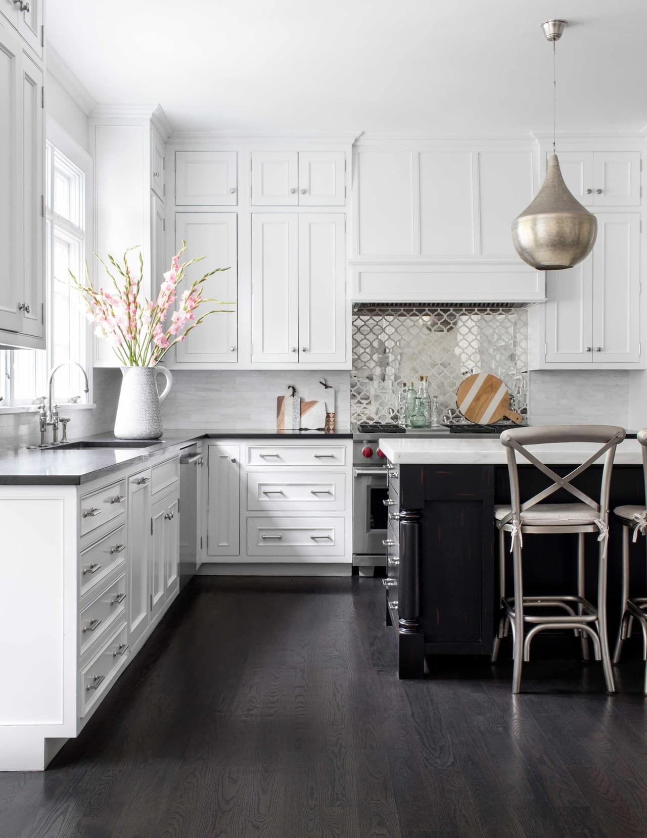 Kitchen with white inset cabinetry, a dark stained island, patterned tile behind the range and a brass pendant over dark wood floors