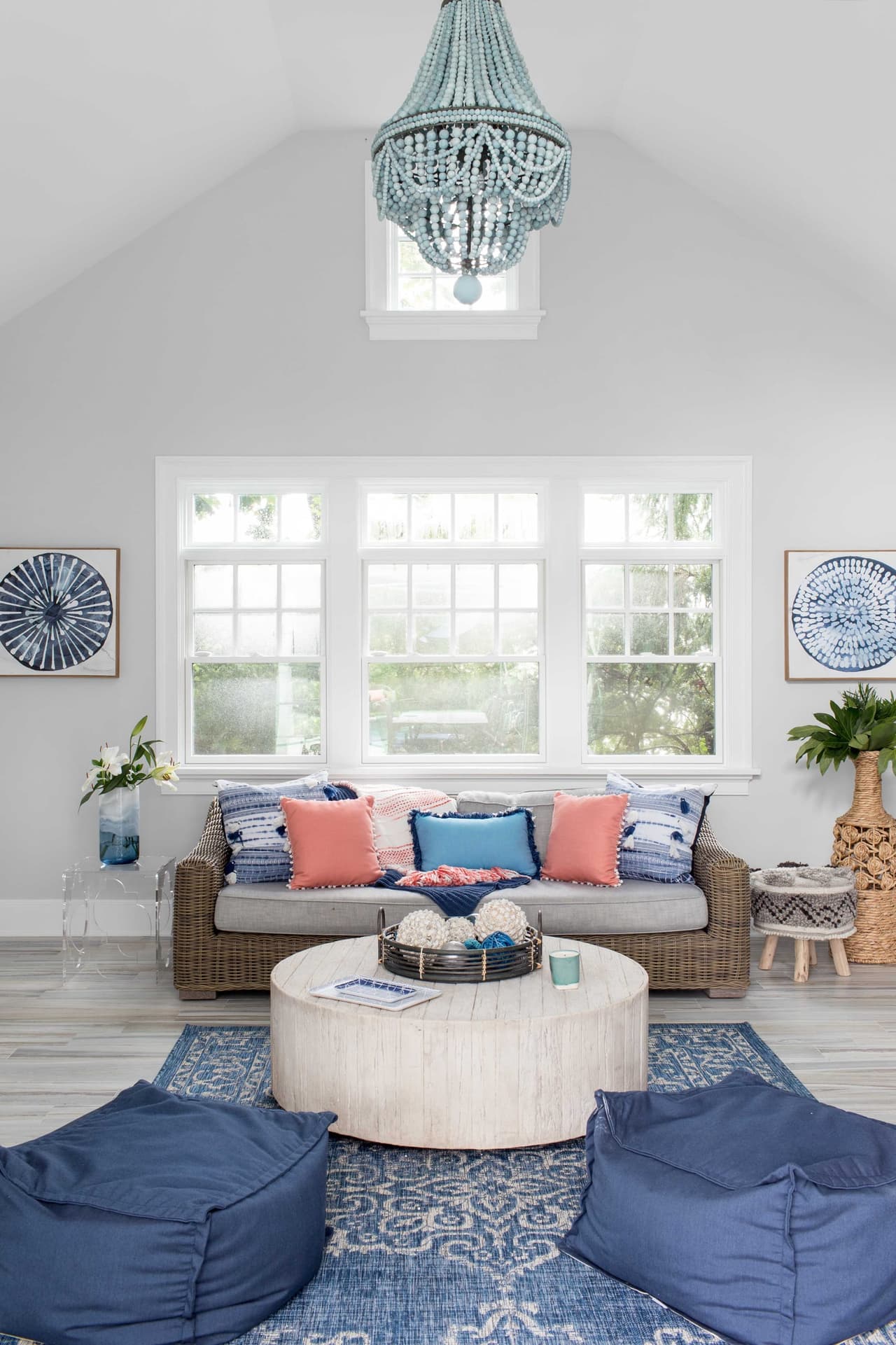 Bonus room under a vaulted ceiling with a beaded chandelier, floor cushions and a round upholstered ottoman