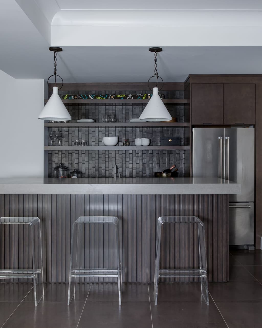 Basement bar in the Mroz family home in Westfield, NJ, with a corrugated metal front, two conical pendants and a tiled back wall with floating shelves